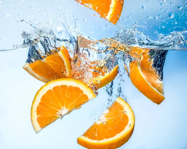 Frutos de naranja caen profundamente bajo el agua con un gran chapoteo — Foto de Stock