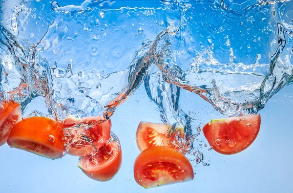 Tomaat. groenten vallen diep onder water met een grote plons — Stockfoto