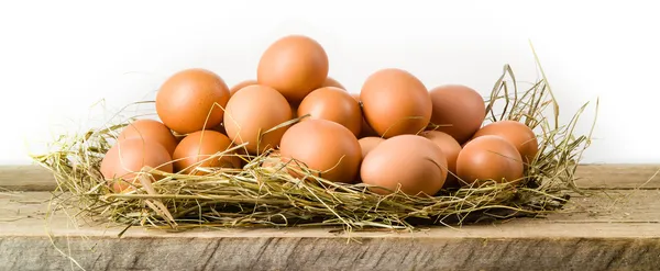 Huevos de pollo en el nido de heno. Aislado sobre blanco. Alimentos ecológicos — Foto de Stock