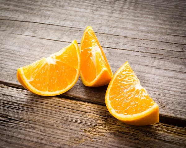 Fruta naranja orgánica. Rebanadas sobre fondo de madera — Foto de Stock