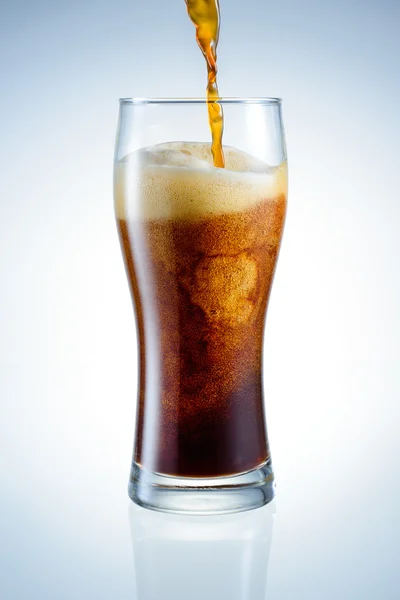 Cerveja escura está derramando no copo — Fotografia de Stock