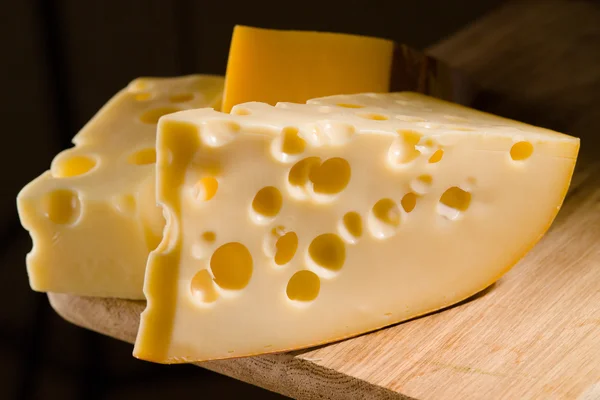 Queijo em tábua de madeira. Fundo escuro — Fotografia de Stock