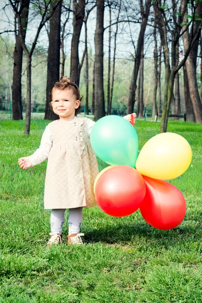 Flicka innehav ballonger i park — Stockfoto