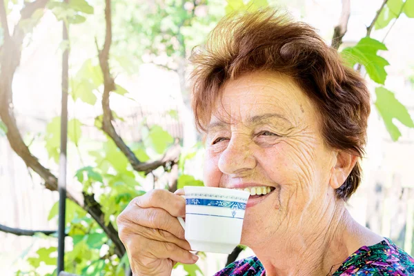 Старая женщина пьет кофе — стоковое фото