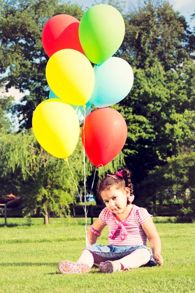 Küçük kız holding renkli balonlar — Stok fotoğraf