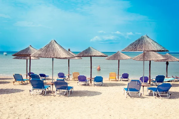 Paraplyer och stolar på stranden — Stockfoto