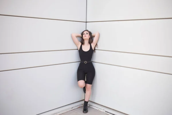 Full body of young woman in black suit and shoes looking at camera while standing in in fashion pose