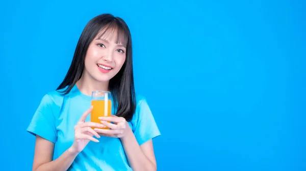 Beautiful beauty Asian woman cute girl with bangs hair style in blue shirt feel happy drinking orange juice for good health on  blue background with copy space - lifestyle beauty woman healthy concept