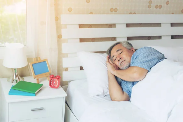 Senior male , old man sleeping on the pillow on white bed room in the morning - lifestyle senior male good health concept