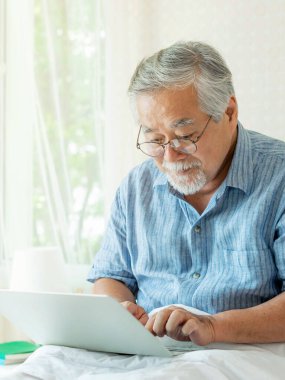 Son sınıf öğrencisi dizüstü bilgisayar kullanıyor. Gülümsüyor. Evde yatakta mutlu hissediyor.