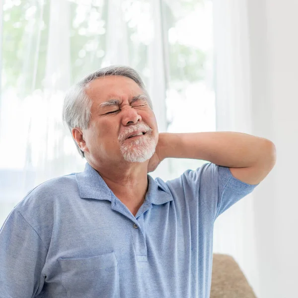 Senior Asian man , old man he wake up and sat on sofa , He had pain in the nape of his neck caused by sleeping on a pillow that is not correct posture - Senior people unhealthy diseased concept