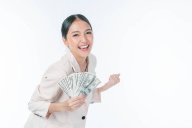 Başarılı, güzel Asyalı iş kadını elinde tuttuğu parayla mutlu bir şekilde doluyor. Beyaz arka planda izole edilmiş Amerikan doları, iş başarısı konsepti.