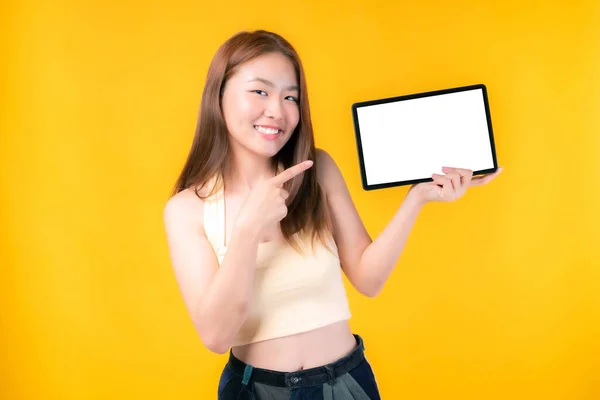 スマートフォンを示す美しいアジアの若い女性 空白の画面を持つタブレット電話コンピュータ 白い画面 黄色の背景に隔離された広告バナーのための空のコピースペース 画像をモックアップ — ストック写真