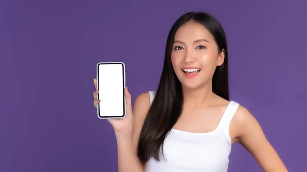美しいアジアの若い女性の肖像画が白い画面でスマートフォンを示しています 紫の背景に隔離された黒い画面 モックアップ画像 — ストック写真