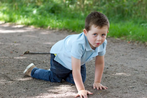 Niño arrastrándose a lo largo de un sendero arbolado — Foto de Stock