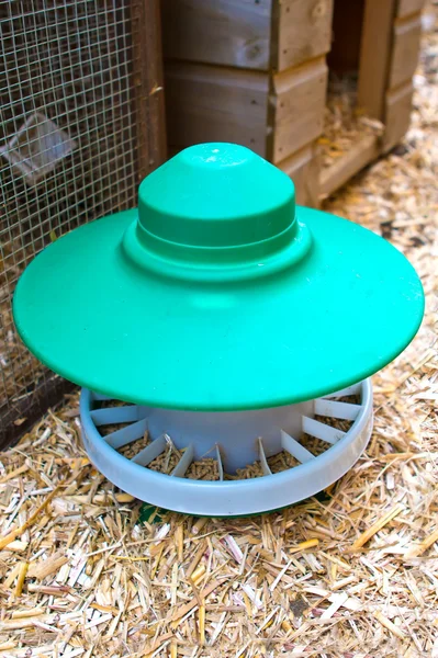Grüner Hühnerfutterautomat aus Plastik im Lauf — Stockfoto