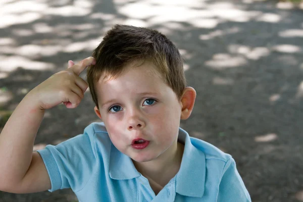 Mały chłopiec zarysowania głowę — Zdjęcie stockowe