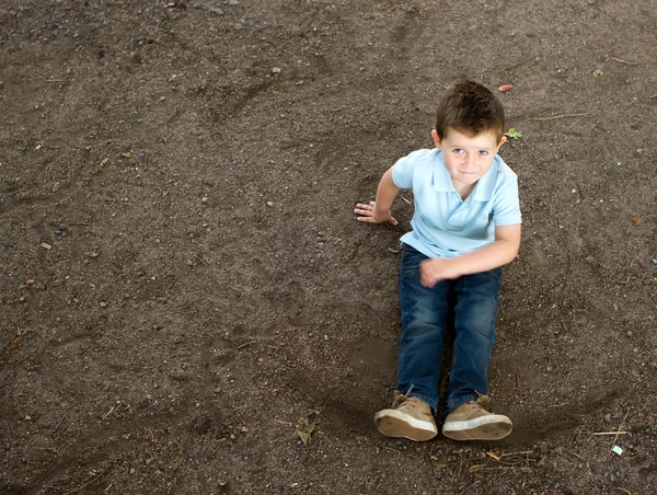 Boy sitting on a stony woodland path — Stock Photo, Image