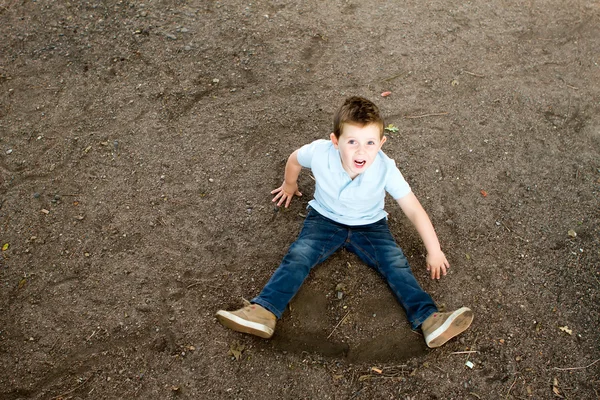 Junge sitzt auf einem steinigen Waldweg — Stockfoto