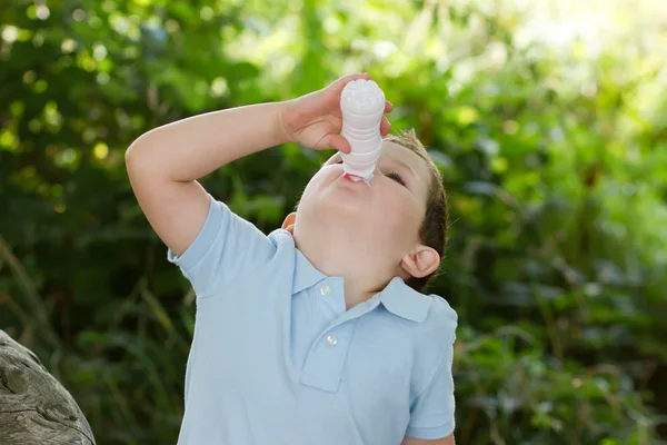 Liten pojke dricka mjölk från en liten vit flaska — Stockfoto
