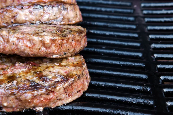 Beef quarterpounder burgers begin to cook on the gas barbecue — Stock Photo, Image