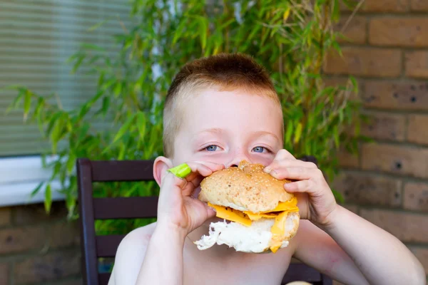 Little boy eating a huge burger — Stock Photo, Image