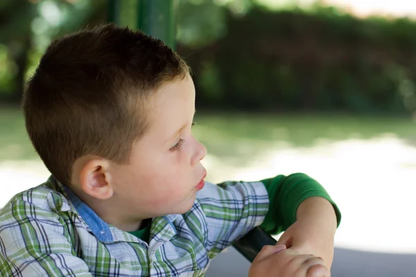 Мальчик в парке, выглядывающий мыслящим — стоковое фото