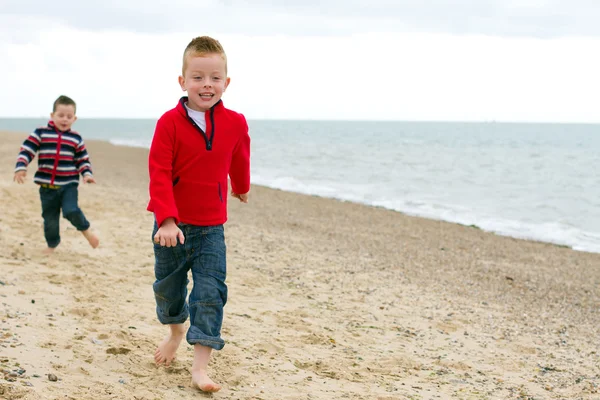 Two brothers running on the beach together — Stock Photo, Image