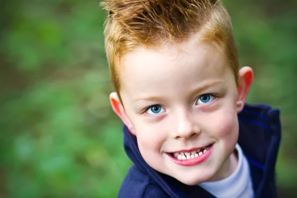 Kleine jongen glimlachend in het bos — Stockfoto