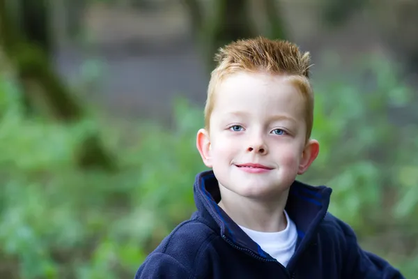 Kleine jongen glimlachend in het bos — Stockfoto
