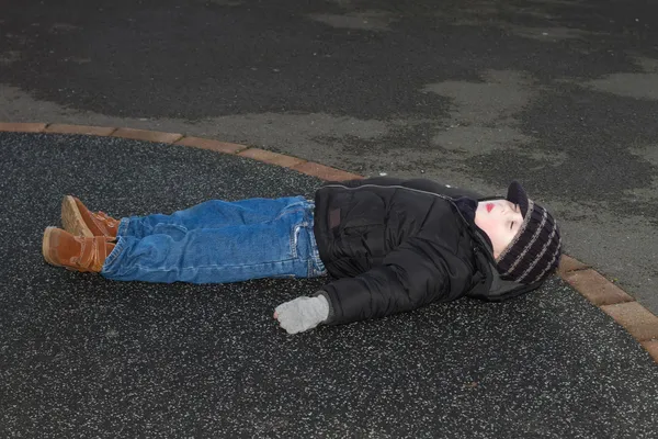 Pequeño chico derribado fuera en asfalto — Foto de Stock