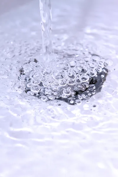 Acqua che scorre lungo un foro del lavandino del bagno — Foto Stock