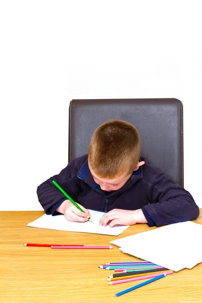 Rapaz que desenha com lápis em uma mesa — Fotografia de Stock