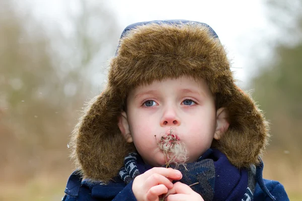 Young boy blowing seeds on a cold winters day — Stock Photo, Image
