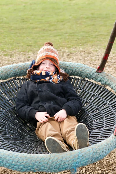 Happy young boy playing at the park on a cold day — Stock Photo, Image