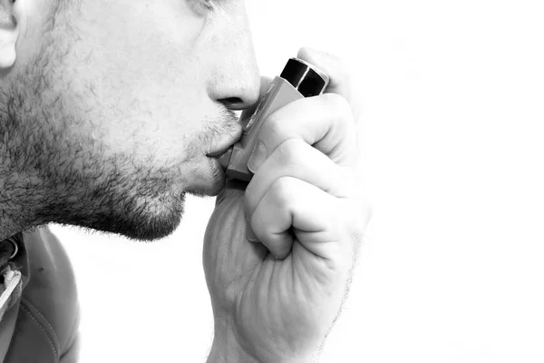 Man inademen zijn astma pomp Stockafbeelding