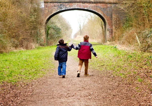 Brothers holding hands together on a country path Stock Photo