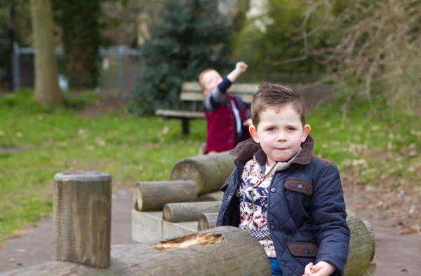 Pequeno menino puxando um triste rosto no parque — Fotografia de Stock