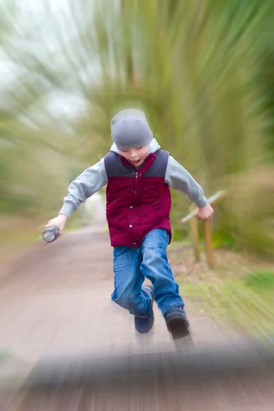 Niño jugando a un parque en una mañana fría con ráfaga de velocidad e — Foto de Stock