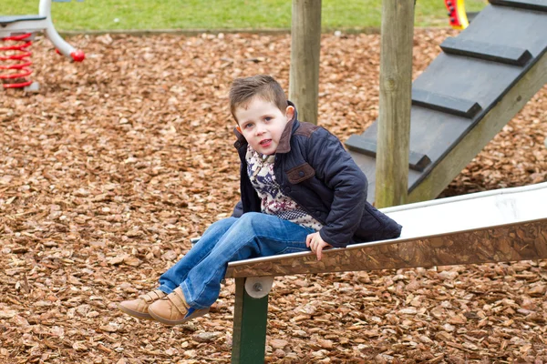 Маленький мальчик играет в парке холодным утром — стоковое фото