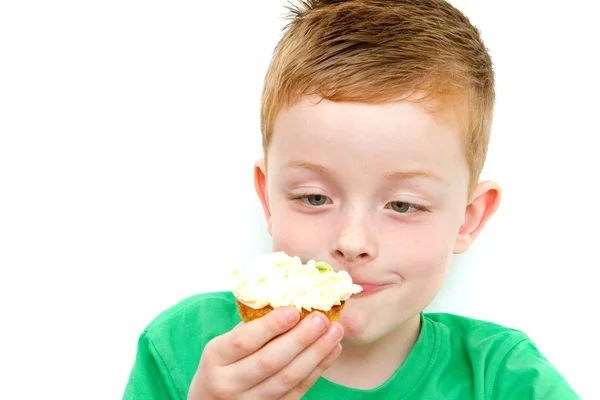 Handsome little boy eating a fresh cream cup cake with messy fac — Stock Photo, Image