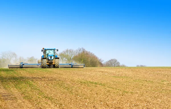 Blauer Traktor pflügt im Frühjahr die Felder lizenzfreie Stockbilder