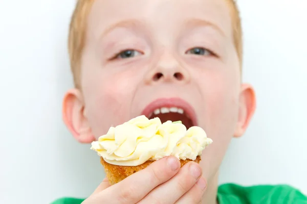 Handsome little boy eating a fresh cream cup cake with messy fac — Stock Photo, Image