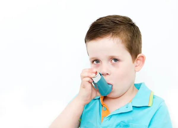 Little boy using his asthma pump Royalty Free Stock Photos