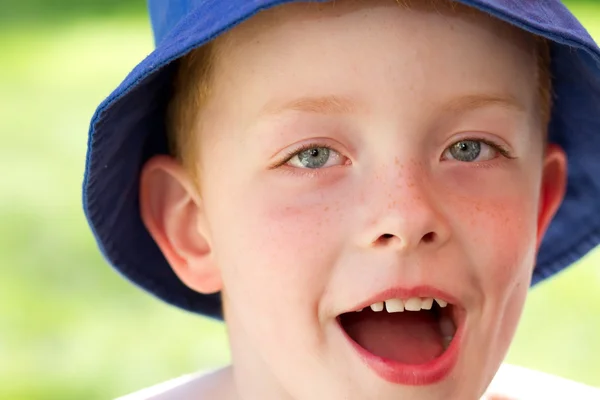 Lindo niño pequeño con un sombrero de sol en el jardín sonriendo de alegría — Foto de Stock