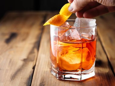 Bir adam kayaya portakal kabuğu koyar. Negnoni kokteyli. Boşluğu kopyala.