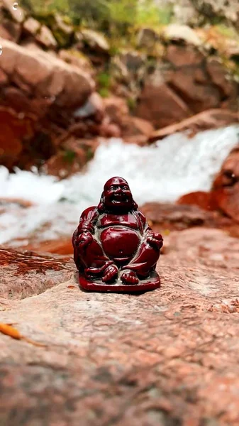 A vertical photo of a buddha in nature