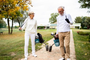 Golf takımlı kıdemli arkadaşlar golf sahasına doğru yürüyorlar..
