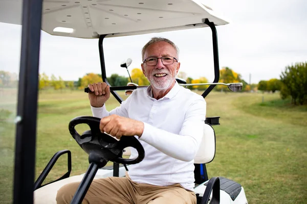 Portrait of rich senior golfer in golf car enjoying nice weather outdoors.