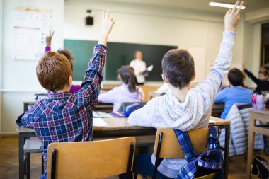 Öğretmenlerinin sorusuna el kaldırarak cevap veren öğrenciler..